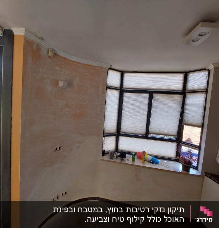 קיר צבוע חלקית עם חלון גדול וכלי עבודה על אדן החלון